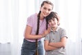 smiling teenage girl embracing little brother with crossed hands Royalty Free Stock Photo