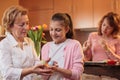 Smiling teenage girl giving decorated Easter eggs to her grandmother