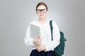 Smiling teenage girl in glasses holding green backpack and laptop Royalty Free Stock Photo