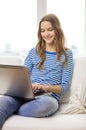 Smiling teenage girl with laptop computer at home Royalty Free Stock Photo