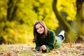 Smiling teenage girl lying on autumn maple leaves at fall outdoors. Portrait of a beautiful smiling teenager. Young teen Royalty Free Stock Photo