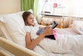 Portrait of smiling teenage girl lying in bed and browsing internet on digital tablet Royalty Free Stock Photo