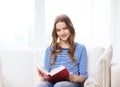 Smiling teenage girl reading book on couch Royalty Free Stock Photo