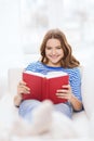 Smiling teenage girl reading book on couch Royalty Free Stock Photo