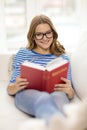 Smiling teenage girl reading book on couch Royalty Free Stock Photo