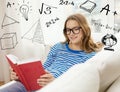 Smiling teenage girl reading book on couch Royalty Free Stock Photo