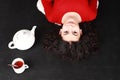 Smiling teen girl in red lying aside of tea cup and teapot Royalty Free Stock Photo