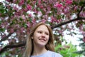 Smiling teenage girl in sakura flowers in spring. Hanami celebration in sakura blooming garden.