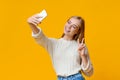 Smiling teenage girl taking selfie on smartphone, showing peace gesture Royalty Free Stock Photo