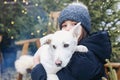 Smiling teenage girl in warm clothes holding cute white puppy in arms Royalty Free Stock Photo