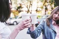 Smiling teenage girls with coffee cups on street. Drinks and friendship concept