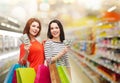 Smiling teenage girls with shopping bags and money Royalty Free Stock Photo