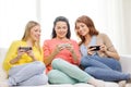 Smiling teenage girls with smartphones at home