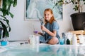 Smiling teenage redhead girl is holding bunch of brushes in hands Royalty Free Stock Photo