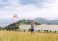 Smiling teenager boy with flying colorful kite on the high grass meadow in the mountain fields. Happy childhood moments or outdoor Royalty Free Stock Photo