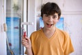 Smiling teenager boy with white paint roller and dirty face make repaint Royalty Free Stock Photo