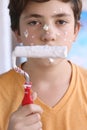 Smiling teenager boy with white paint roller and dirty face make repaint Royalty Free Stock Photo