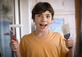 Smiling teenager boy with white paint roller and dirty face make repaint Royalty Free Stock Photo
