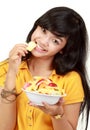 Smiling teenager eating a bowl of cut fruits Royalty Free Stock Photo