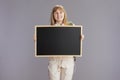 smiling teenager girl in beige tracksuit showing blank board Royalty Free Stock Photo