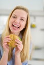 Smiling teenager girl eating sandwich in kitchen Royalty Free Stock Photo