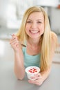 Smiling teenager girl eating yogurt in kitchen Royalty Free Stock Photo