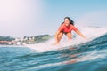 Smiling teenager surfing, photographed from the water, on a sunny day with the green mountains in the background