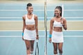 Smiling tennis players holding their rackets on the club court. Two young friends bonding and talking after a practice Royalty Free Stock Photo