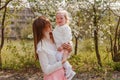 Smiling thirty-year-old woman and two-year-old baby girl amid flowering apple trees in spring Royalty Free Stock Photo