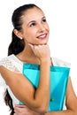 Smiling thoughtful woman holding plastic folder with fist on chin