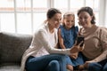 Smiling three generations of women using cellphone together Royalty Free Stock Photo