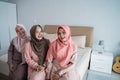 Smiling three hijab women sitting on the bed in the bedroom