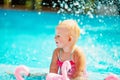 Smiling toddler girl swimming in the pool with pink flamingos