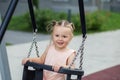 Smiling toddler girl swinging on playground swing. Kid playing on school or kindergarten yard Royalty Free Stock Photo