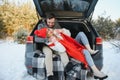 Smiling together. Nice couple have weekend at countryside at winter time. Sitting on the rear part of modern car Royalty Free Stock Photo