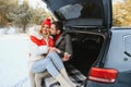 Smiling together. Nice couple have weekend at countryside at winter time. Sitting on the rear part of modern car Royalty Free Stock Photo