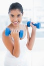 Smiling toned brunette holding dumbbells