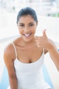 Smiling toned brunette sitting on floor showing thumb up