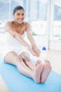 Smiling toned brunette sitting on floor stretching legs