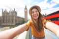 Smiling tourist girl taking self portrait in London, UK. Selfie photo of happy woman traveling in London with Big Ben tower, Royalty Free Stock Photo