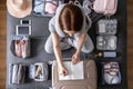 Smiling tourist woman packing suitcase to vacation writing paper list getting ready to travel trip Royalty Free Stock Photo