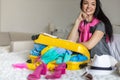 Smiling tourist woman packing suitcase to vacation writing paper list getting ready to travel trip Royalty Free Stock Photo