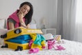 Smiling tourist woman packing suitcase to vacation writing paper list getting ready to travel trip Royalty Free Stock Photo