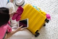 Smiling tourist woman packing suitcase to vacation writing in tablet getting ready to travel trip Royalty Free Stock Photo