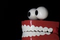 A smiling toy prosthesis, with white teeth and large eyes isolated against a black background. Royalty Free Stock Photo