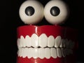 A smiling toy prosthesis, with white teeth and large eyes isolated against a black background. Royalty Free Stock Photo