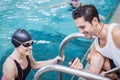 Smiling trainer showing stopwatch at swimmer