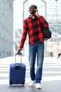 Smiling travel man walking with suitcase and talking on mobile phone Royalty Free Stock Photo