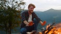 Smiling traveler warm fire on camp. Joyful millennial rest in forest closeup.