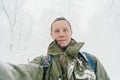 Smiling traveler man taking selfie in snowy forest.